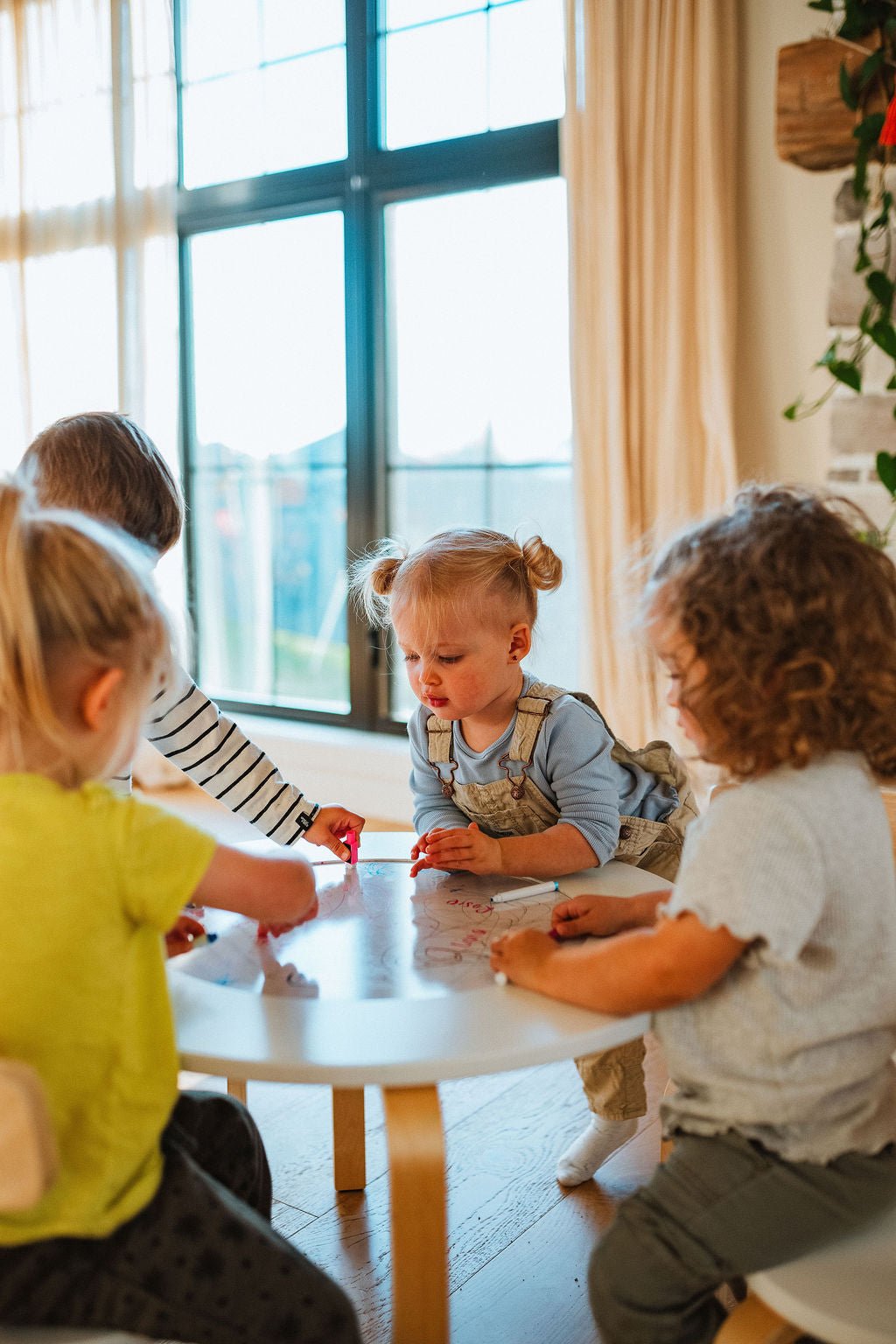 Four toddlers drawing together on the whiteboard top of the Montessori activity table